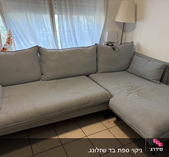 ספה אפורה עם כתמים על רצפת אריחים